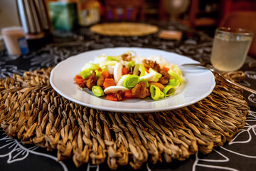 Chicken piece with vegetable and rice on white plate on bamboo pad on table,restaurant.
