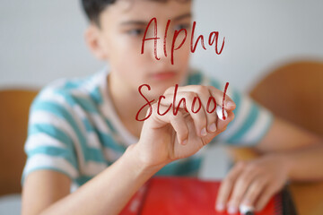ALPHA SCHOOLS. Preteen boy writing text on the screen with a red marker