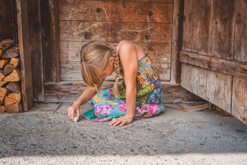 Kind malt am Boden mit Malkreide