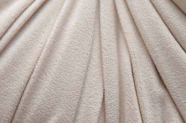 Close-up of cream fleece fabric with flowing folds, showcasing softness, warmth, and cozy texture © TeacherPhoto