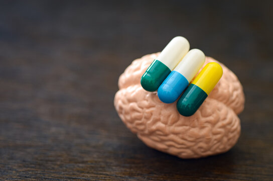 Human brain with pharmaceutical capsules and stop sign symbolizing medication impact and mental health warning