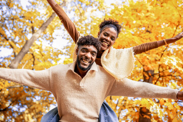 Happy African American Couple Enjoying Piggyback Ride in Autumn Park
