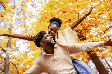 Happy African American Couple Enjoying Piggyback Ride in Autumn Park