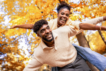 Happy African American Couple Enjoying Piggyback Ride in Autumn Park