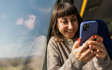 Train passenger. A woman texting on a mobile phone on a train. Side view of a woman holding a phone. The girl is using social media. T