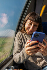Train passenger. A woman texting on a mobile phone on a train. Side view of a woman holding a phone. The girl is using social media. T