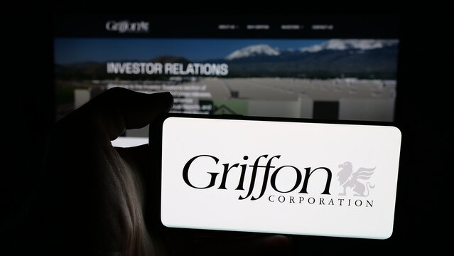 Stuttgart, Germany - 12-19-2025: Person holding mobile phone with logo of US conglomerate company Griffon Corporation on screen in front of web page. Focus on phone display.