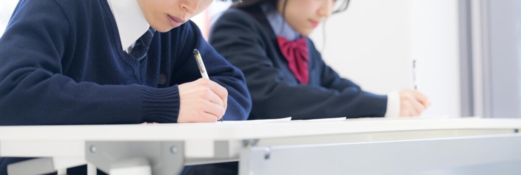 学校や塾などで受験対策の模試のテストを受ける高校生の男女の顔無しのバナー
