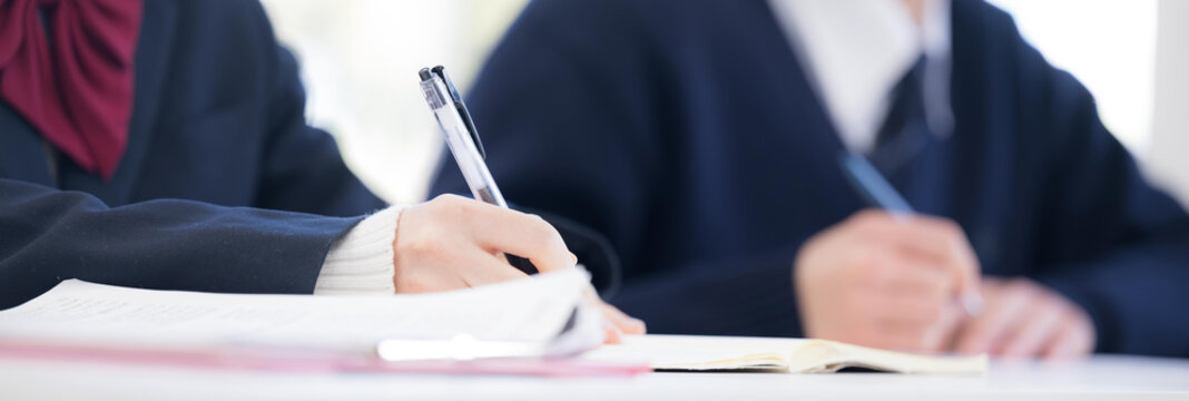 高校生が学校の教室や塾の授業で勉強をするノートを書くシーンの手元のクローズアップ