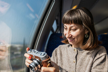 Close-up of a girl holding a film camera and about to take a picture. Train journey.