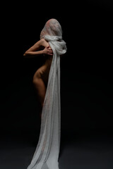 Red woman poses gracefully in nude with flowing fabric on a dark background