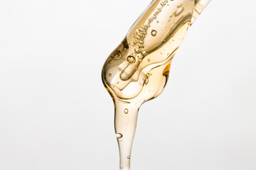 Essential oil in a pipette slowly drips down, close-up of the aromatherapy and massage product.