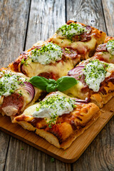 Pizza with sausage, mozzarella cheese, tomato sauce, red onion and broccoli yogurt on wooden table	