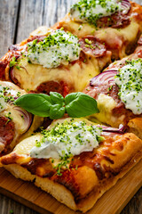 Pizza with sausage, mozzarella cheese, tomato sauce, red onion and broccoli yogurt on wooden table	