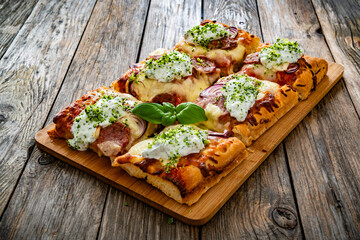 Pizza with sausage, mozzarella cheese, tomato sauce, red onion and broccoli yogurt on wooden table	