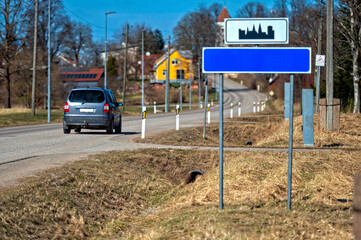 Blank road sign mock-up placed beside a quiet country road on a sunny day