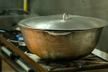Close-up of a large traditional stainless steel pot with lid on a professional gas stove in a kitchen in Costa Rica