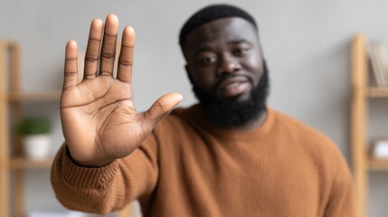 Man with beard raises hand at home during sunny afternoon in casual sweater