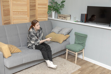 Fototapeta premium Woman preparing to watch television in her room, using a remote control for relaxation and entertainment before sleep.
