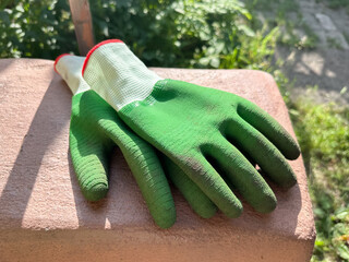 Green gardening gloves on stone surface in sunlight