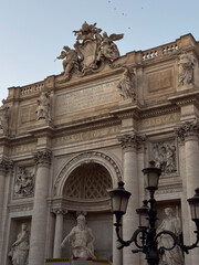 Close-up of historic Roman building with detailed sculptures, columns, and vintage street lamps in Rome, Italy.