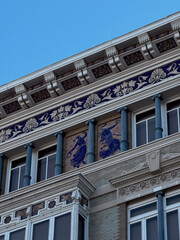 Ornate facade of a historic building in Valencia with colorful ceramic tiles and architectural detail on upper windows.