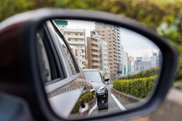 都会の渋滞と街並みを映し出す走行中の車のサイドミラー