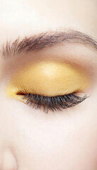 close up of female eye with yellow makeup