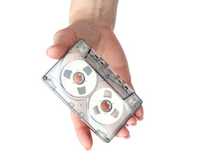 Female hand holding a compact audio cassette as an invitation to listen to music. Vintage analog audio, retro technology and nostalgia concept. Isolated object on transparent background.