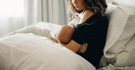 Mother nursing baby on a bed