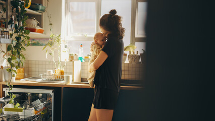 Mother holds baby in cozy kitchen