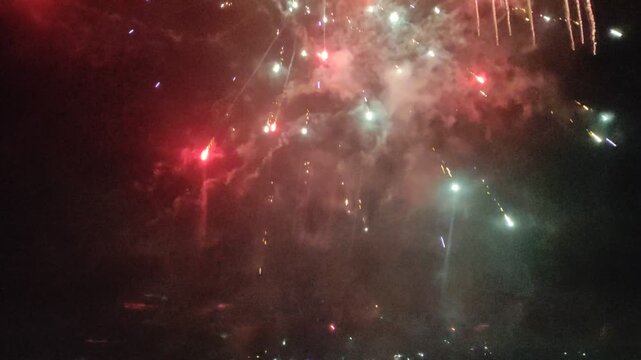 New Year fireworks over night city with explosions, flashes and smoke. Video with sound