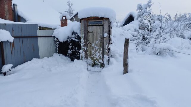 Man approaches an old wooden rural outhouse and opens the door in winter. First person view video with sound