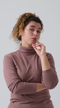 Vertical video of a confused woman facepalming, thinking, and shrugging her shoulders, isolated on a white background.