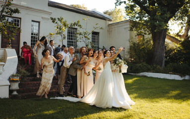 Outdoor micro wedding celebration with two brides taking a group selfie with guests