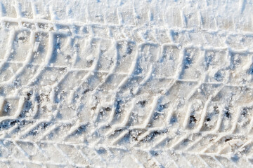 Obraz premium Car tire tracks forming a repeating pattern in fresh white snow, top view winter background with minimal texture and strong graphic lines. Directly above.