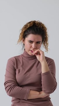 Vertical video of a pensive woman thinking hard, getting stressed, and then having a brilliant idea. Isolated on a white background.