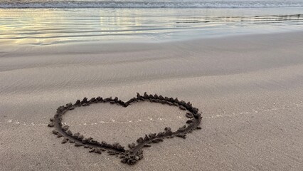 Heart shape drawn in wet sand on empty beach at calm ocean shoreline