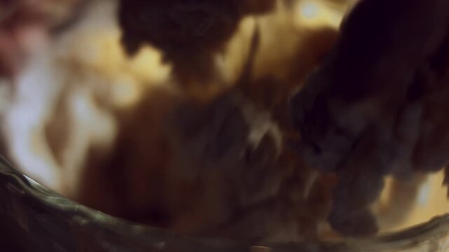 Macro view of female hand mixing food ingredients for dough in a glass bowl