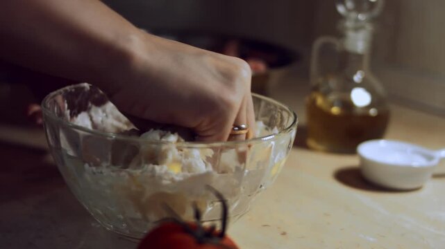 Close-up female hand preparing dough in a glass bowl