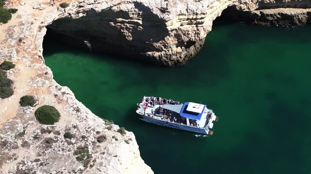 Aerial drone shot of boat sightseeing at Benagil sea caves and Atlantic Ocean coastline in Benagil, Algarve, Portugal, Europe