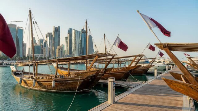 Traditional Wooden Dhow Boats With Qatar National Flags Docked At The Pier Of Doha Harbor Against Modern City Skyline Skyscrapers At Sunset