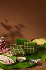 Stacked Chung cakes surrounded by dong leaves and ingredients, modern Vietnamese Tet food...