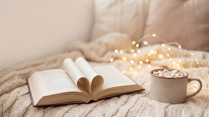 Cozy book and cocoa on bed. Open book pages form heart, book beside mug with marshmallows and fairy lights for valentinesday, christmas nights, winter self care, hygge mood, soft blanket