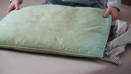 Human hands demonstrate a green pillow with dirty yellow stains sweat or saliva in a living room. Conscious home care and sustainable living concept. top view
