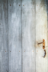 Aged wooden door of abandoned rural house, rustic texture background symbolizing time, decay, history and solitude