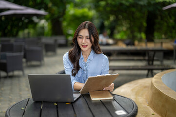 Asian businesswoman working remotely at outdoor cafe table