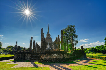 Stupa mit einer Buddha-Figur davor in der Mittagssonne