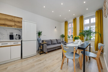 Salon w nowoczesnym apartamencie – jadalnia ze stolikiem z talerzami, duży zielony kwiat w doniczce © arteffect.pl