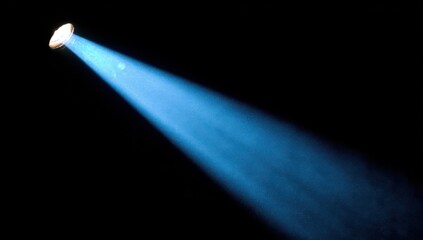Bright blue spotlight beam against dark background for dramatic effect